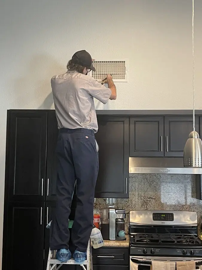Technician inspecting an air vent during HVAC service in Dranesville